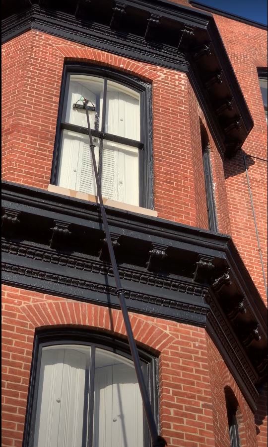 Cleaning the windows of a brick building with a water-fed pole
